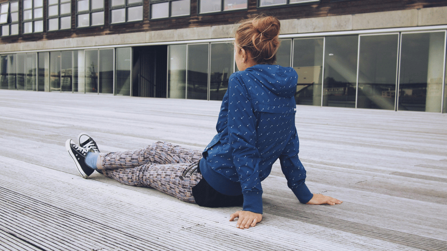 A young woman sitting with legs outsretched on a pavement 